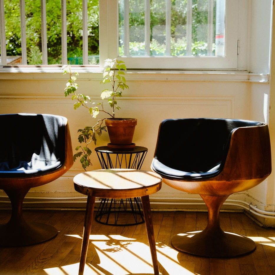Two moulded chairs and a small side table in afternoon light