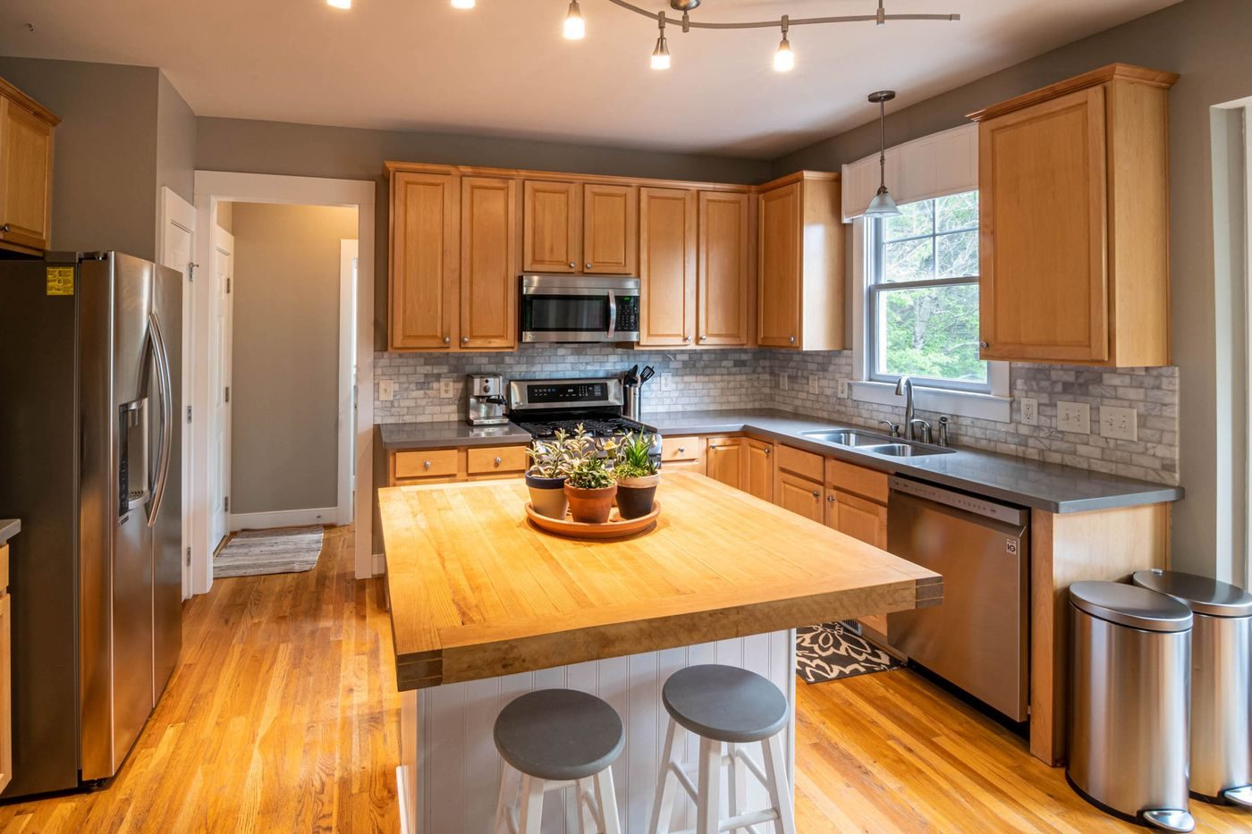 A kitchen with honey-toned wood cabinets and a butcher block island