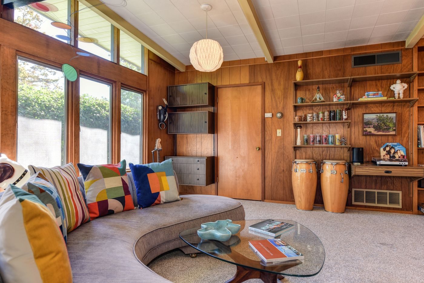 A panelled living room with built-in shelving, collected objects and warm light