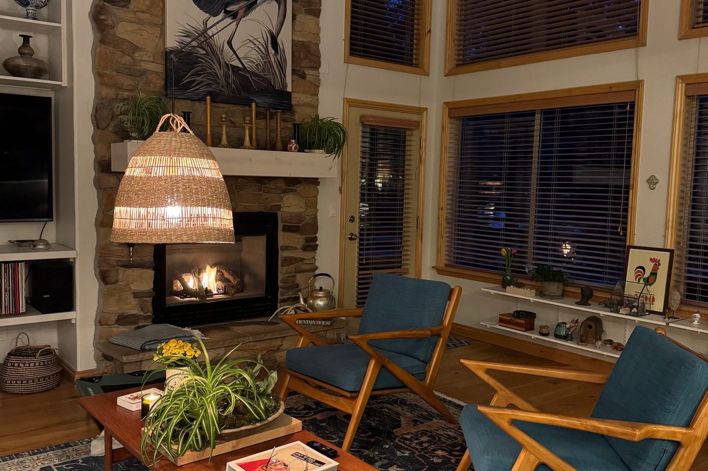 A living room around a stone hearth with teak-framed chairs