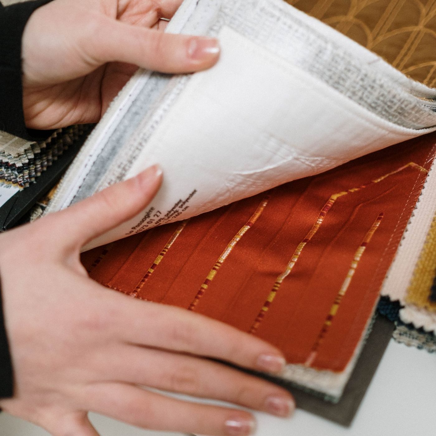 Hands turning a page of terracotta fabric swatches