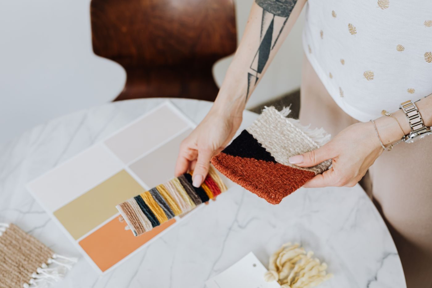 A hand laying out colour chips and carpet samples in earth tones