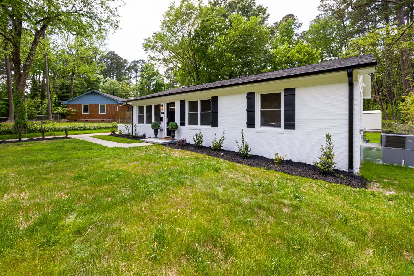 A long low brick ranch viewed from the side, set among pines
